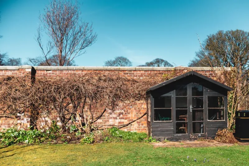 Dark timber garden shed in a British walled garden with neat lawn