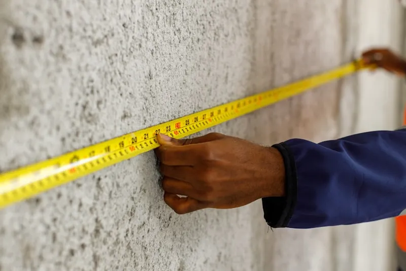 Construction worker measuring dimensions with a tape measure on a building site